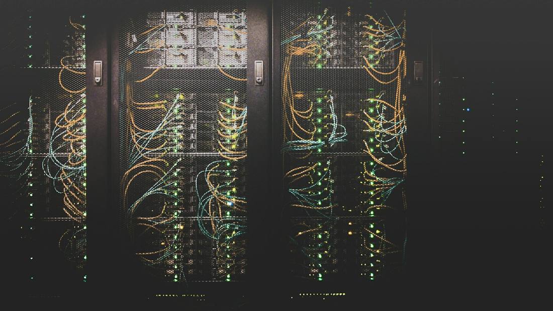 Server racks in a dark data hall with lit fiber cabling